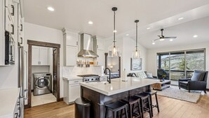 Cocina moderna con una isla central, electrodomésticos de acero inoxidable e iluminación colgante.
