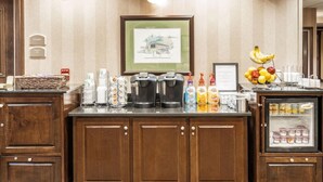 A hotel reception area with a coffee station, a fruit bowl, and a refrigerator with beverages. - Holiday Inn Oxford (Oxford)