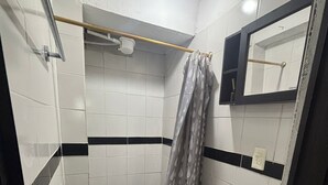 Ein kleines Badezimmer mit Toilette, einer Duschvorhang, einem Handtuchhalter und einem Spiegel.