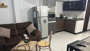 Eine moderne Küche mit Kühlschrank, Mikrowelle und Kaffeemaschine. Ein Essbereich mit Tisch und Stühlen ist ebenfalls vorhanden.