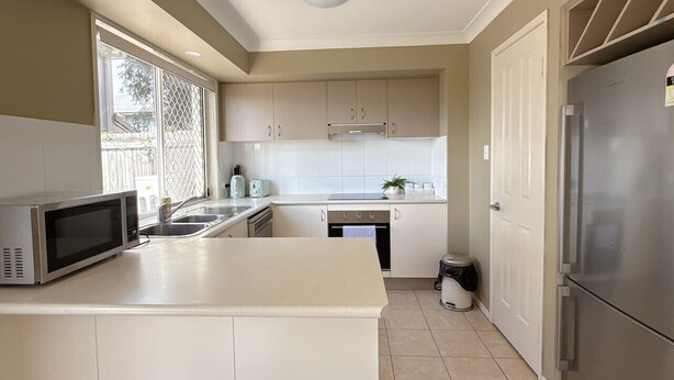 A kitchen with a microwave, sink, stove, and refrigerator. - Family-Friendly 3BR Home Near Calamvale Central (Calamvale)