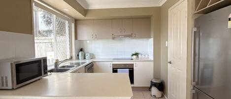 Una cocina equipada con microondas, pileta, estufa y refrigerador.