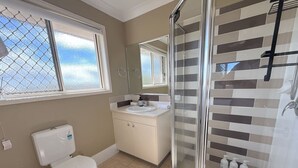 A bathroom with a toilet, sink, and shower area. - Family-Friendly 3BR Home Near Calamvale Central (Calamvale)