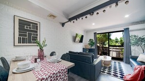 Een moderne woonkamer met een eethoek, een bank, een televisie en uitzicht op het omliggende landschap.