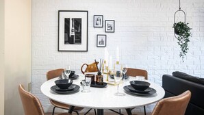 Una mesa redonda de comedor con platos negros y vasos, un sofá de cuero marrón y cuadros en la pared.