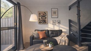 Una sala de estar moderna con un sofá de cuero, una mesa de centro redonda, una lámpara de pie y obras de arte en la pared.