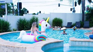 Ein Swimmingpool mit einem Einhorn-Schwimmpfiff, Liegestühlen und einer Steinummrandung.