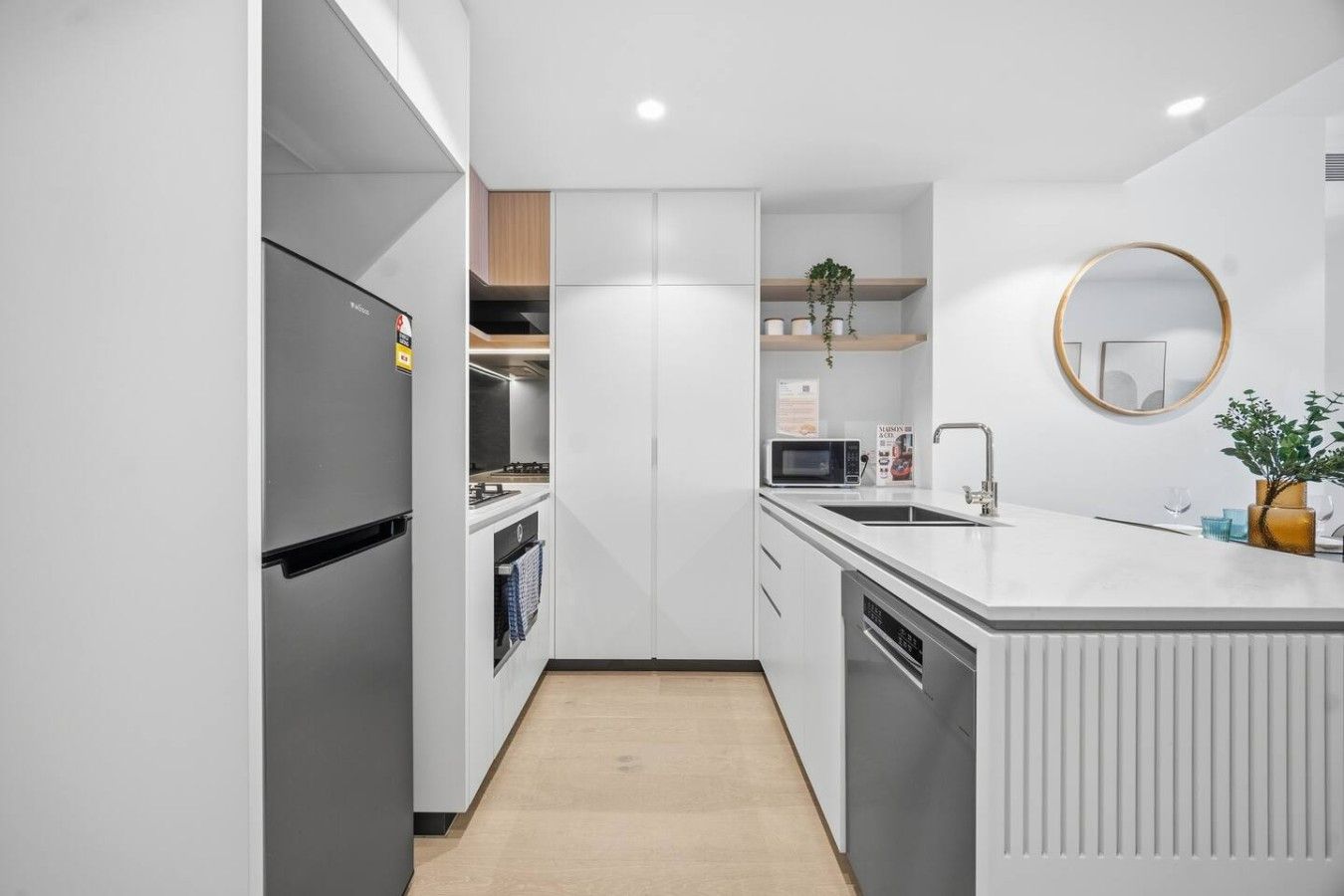 A modern kitchen with a built-in refrigerator, microwave, and sink.