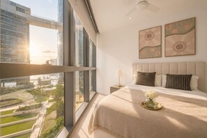 A hotel room with a large window, a bed with a beige blanket, and two wall art pieces. - Iconic Queen’s Wharf 2BR Prime CBD Location (Brisbane City)