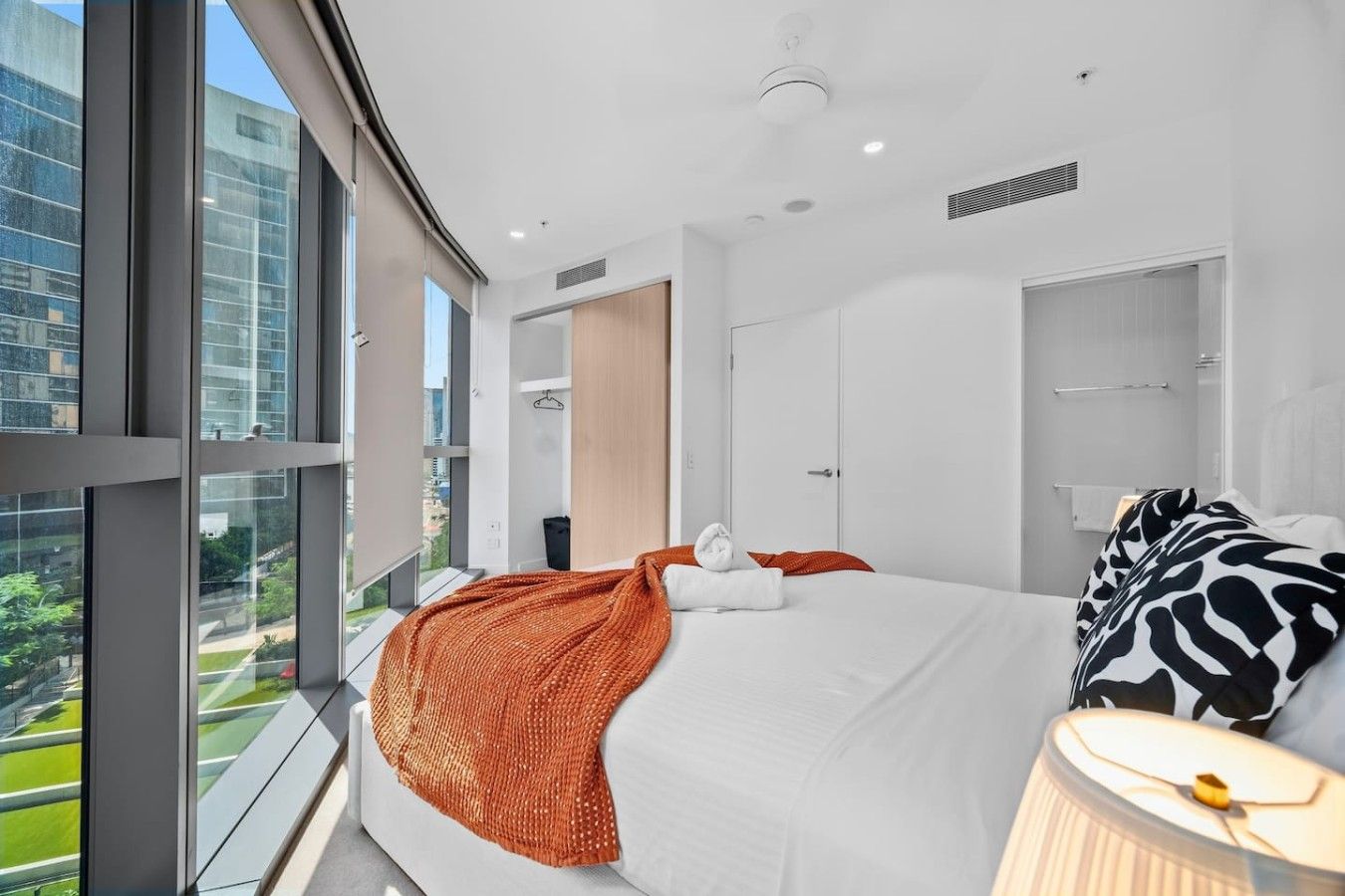 A modern hotel room with a large bed, a view of the city, and a balcony.