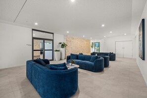 A modern lounge area with seating and a stone accent wall. - Luxury 54F Skyline Apt | Iconic Queen’s Wharf 1BR (Brisbane City)