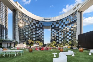 A modern hotel with a curved facade, outdoor seating area, and a well-maintained lawn. - Luxury 54F Skyline Apt | Iconic Queen’s Wharf 1BR (Brisbane City)