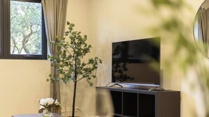 Uma sala de estar com televisão, uma planta e uma mesinha com um vaso.