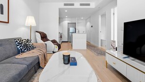 En moderne stue med sofa, massagestol, sofabord og tv.