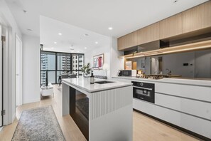 A modern kitchen with a central island, built-in appliances, and a view to the outside. - Landmark Queens Wharf 1BR w/ Pool, Gym & City View (Brisbane City)