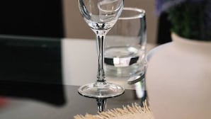 Una copa de vino de vidrio transparente sobre una mesa, con fondo desenfocado.