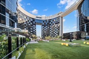 A modern building with a curved facade, a central courtyard with grass, and outdoor seating areas. - Level 43 Sweeping Skyline | Luxury Designer 1BR (Brisbane City)