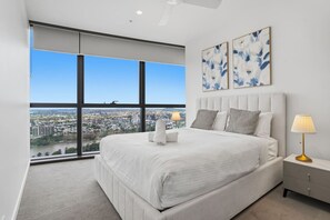 A bedroom with a large window, a bed, a bedside table, and a lamp. - Level 43 Sweeping Skyline | Luxury Designer 1BR (Brisbane City)