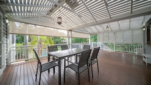 Eine überdachte Terrass mit Holzdeck, einem Tisch und Stühlen sowie Blick ins Grüne.