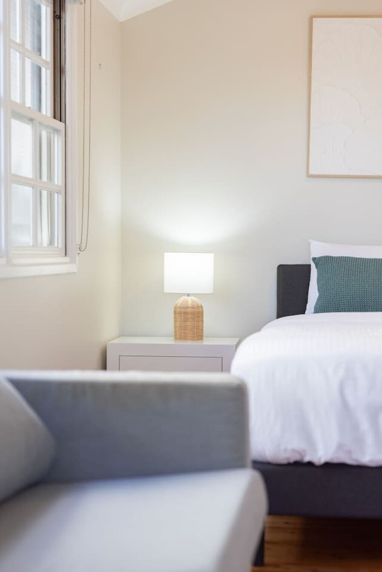 Une chambre à coucher avec un lit, une table de chevet avec une lampe, une fenêtre et une chaise.