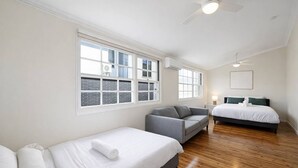 Ein Schlafzimmer mit einem Bett, einer Couch, einem Schreibtisch und einem Fenster.
