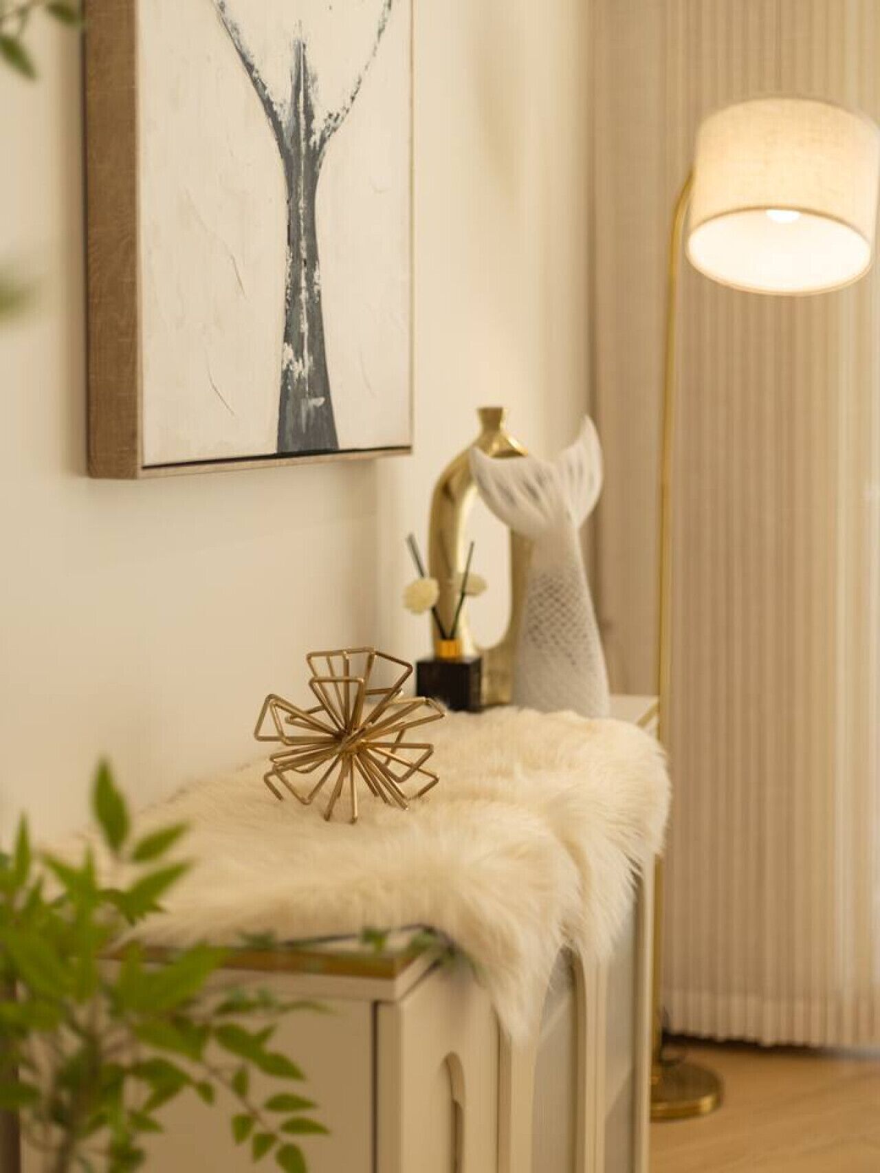 A room with a white cabinet, a gold lamp, and a framed abstract painting on the wall.