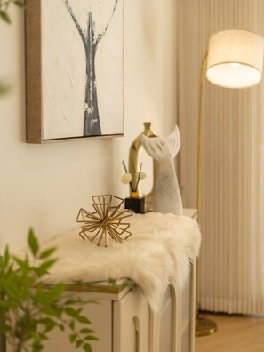 A room with a white cabinet, a gold lamp, and a framed abstract painting on the wall.