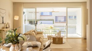 A spacious living room with a sofa, coffee table, and dining area set up for a meal. - Brand-New 4BR Luxury Living Near Airport & Mall (Nundah)