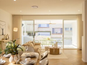A spacious living room with a sofa, coffee table, and dining area set up for a meal.