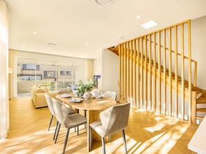 A modern dining area with a wooden table, chairs, and a view of the outside.
