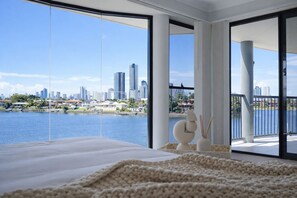 Ein Schlafzimmer mit großem Fenster und Blick auf eine Stadtlandschaft und ein Gewässer.