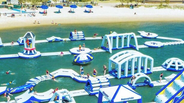 En udendørs vandpark med oppustelige legeområder og en strand.