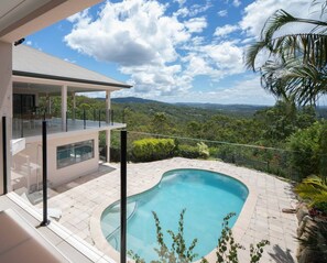 A modern house with a swimming pool, a glass-enclosed balcony, and a view of the surrounding landscape. - Luxury 6BR Hinterland Retreat w/ Pool &Scenic View (Bonogin)
