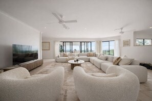 A spacious living room with a large sectional sofa, a coffee table, and a flat-screen TV. - Luxury 6BR Hinterland Retreat w/ Pool &Scenic View (Bonogin)