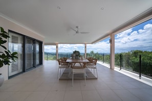Ein geräumiger Balkon mit Essbereich, großen Fenstern und Blick auf die Landschaft.