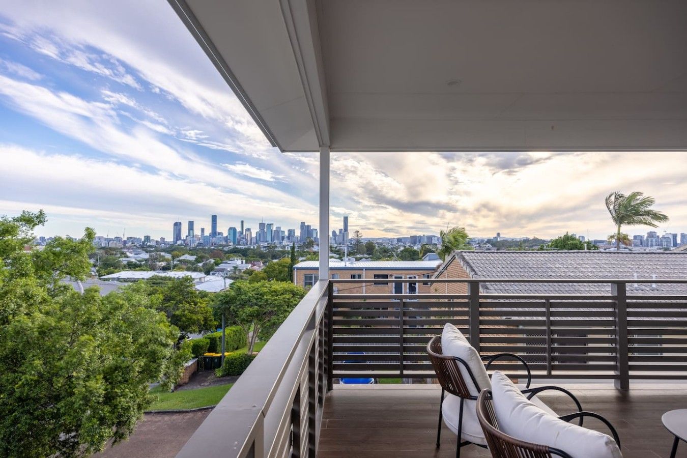 A balcony with a view of a city skyline, a chair, and a table.