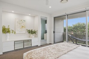 A bedroom with a bed, a bench, a potted plant, a framed artwork, and a sliding glass door leading to a balcony. - Scenic City Views + Pool | Elegant 5BR Residence (Hawthorne)