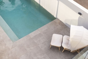 A poolside area with a clear blue pool, two white cushioned chairs, and a glass barrier. - Scenic City Views + Pool | Elegant 5BR Residence (Hawthorne)