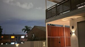 Un edificio moderno con un espacio exterior techado, piscina y cerca de madera.