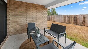 A patio with a brick wall, a wooden fence, and a clear sky. - Newly Furnished Stylish 4BR Getaway with Patio (Park Ridge)