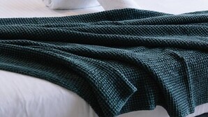 A neatly made bed with a white comforter, a rolled white towel, and a dark green knitted throw. - Newly Furnished Stylish 4BR Getaway with Patio (Park Ridge)