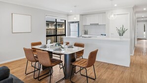 A modern kitchen with white cabinetry, a central island, and pendant lighting. - Newly Furnished Stylish 4BR Getaway with Patio (Park Ridge)