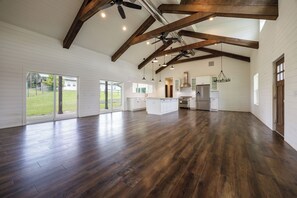 Een ruime keuken met houten balken, een centraal eiland en hanglampen.