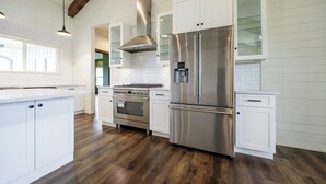 Een moderne keuken met witte kasten, roestvrijstalen apparatuur en een houten vloer.