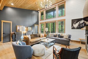 A spacious living room with a large sofa, a coffee table, and a fireplace. - Moonlight Creek Retreat ~ Private Creek, Hot Tub, Fire Pit & More (Ellijay)