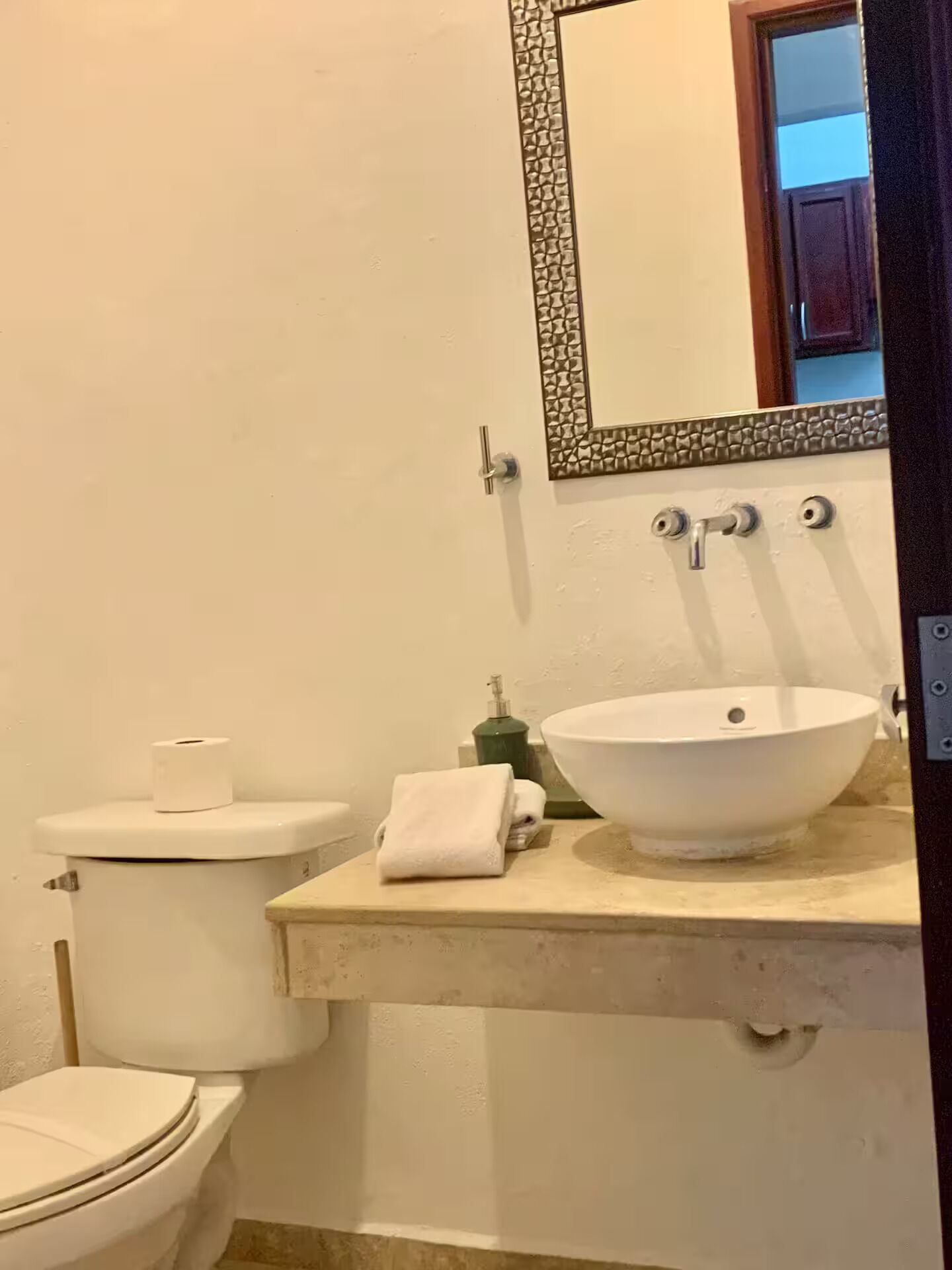 Ein Badezimmer mit Toilette, Waschbecken, Spiegel und Handtuch.