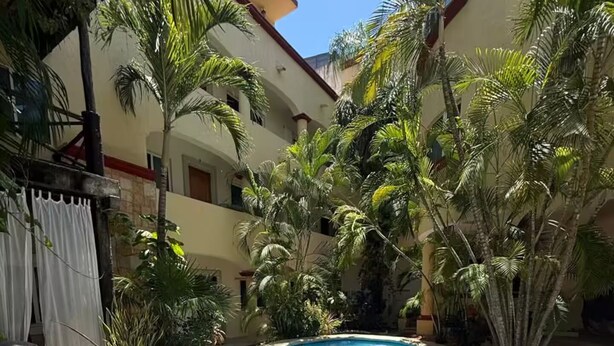 Ein Swimmingpool, umgeben von Palmen und einem Gebäude mit rotem Dach.