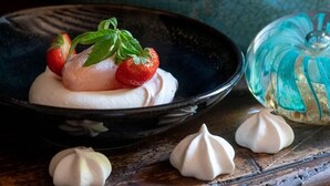 Un dessert aux fraises, surmonté d’une meringue, présenté dans une assiette foncée.