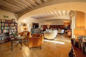 A spacious living room with a curved ceiling, a fireplace, a television, and a bookshelf. - Hotel les Messugues By Alain Llorca (Saint-Paul-de-Vence)