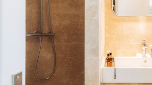 Une salle de bain avec une douche, un lavabo et un miroir.